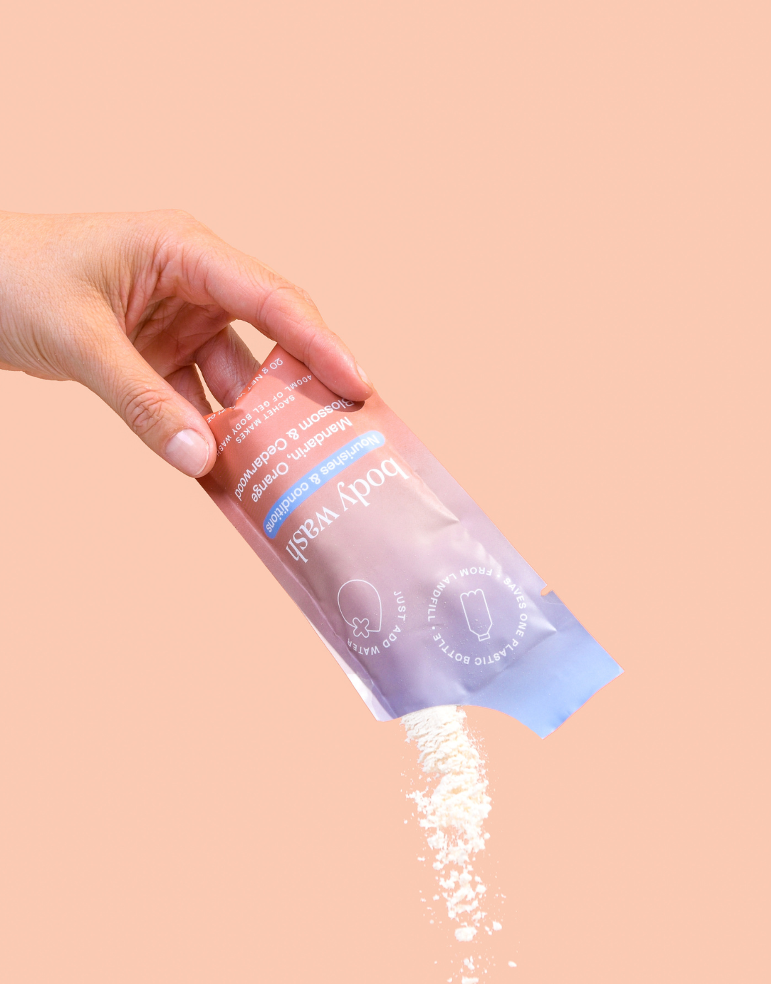 Epzen mandarin orange blossom and cedarwood body wash powder being poured from a refill sachet