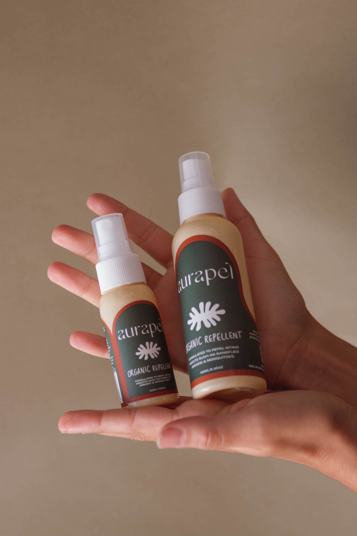 Aurapel 50ml and 125ml bottles held side by side for size comparison