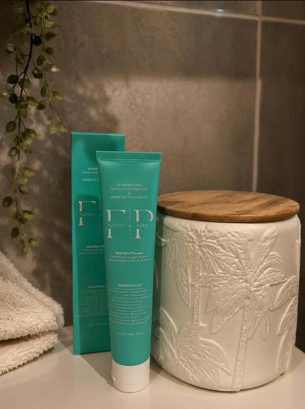 Flossy & Pure Mild Mint toothpaste tube and box in a bathroom setting